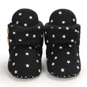 Vista frontal de botas de vellón para bebé negras con estrellas y suela antideslizante