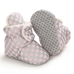 Close-up of pink checkered baby booties with soft non-slip dot soles and fleece lining