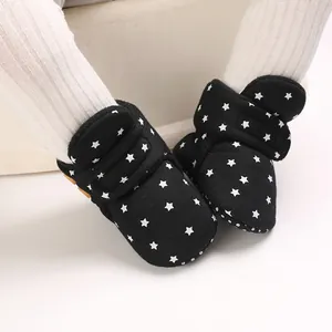 Vista detallada de las botas de nieve para bebé negras con patrón de estrellas blancas