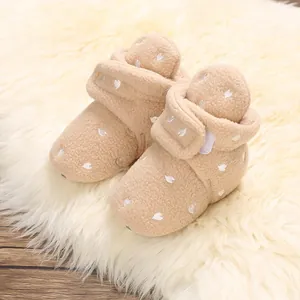 Close-up of warm beige baby booties with white heart embroidery on soft faux fur