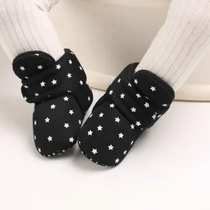 Primer plano de botas de nieve negras para bebé con patrón de estrellas y velcro