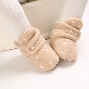 Close-up view of warm fleece baby booties with white heart pattern and soft sole