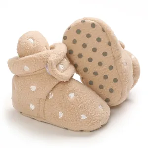Close-up detail of warm beige fleece baby walking boots with heart pattern and anti-slip sole