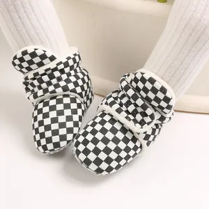 Close-up of black and white checkered baby winter boots with warm fleece lining