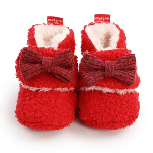 Frontale Nahaufnahme warmer roter Baby-Fleece-Stiefel mit eleganten Strickschleifen