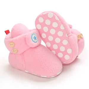 Dettaglio di scarponcini da neve rosa in peluche per neonati con toppa a stella.