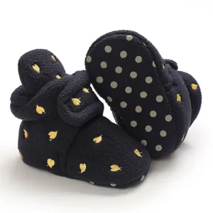 Detail view of navy baby booties with gold leaf embroidery and non-slip sole dots.