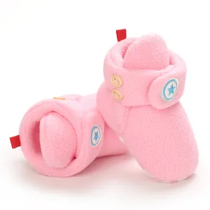 Dettaglio stivaletti da neve rosa per neonato con stella e bottoni in legno.
