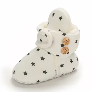 Primer plano de botas de nieve blancas para bebé con estrellas negras y forro polar