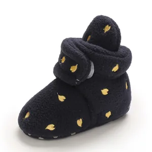 Primo piano di scarpina neonato in pile blu navy con ricamo cuore dorato elegante