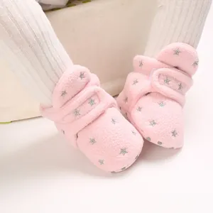 Close-up detail of pink fuzzy baby boots with silver star patterns and warm fleece lining.