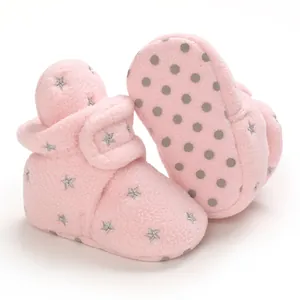 Close-up view of pink fuzzy baby snow boots featuring star patterns and non-slip soles