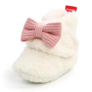 Nahaufnahme eines weißen, flauschigen Baby-Winterstiefels mit rosa Strickschleife