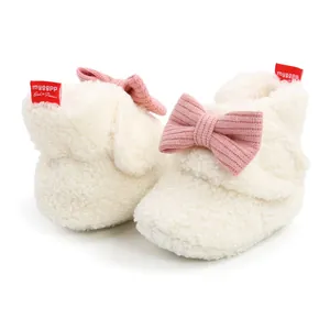 Detailansicht von flauschigen cremeweißen Baby-Schuhen mit einer weichen rosa Schleife
