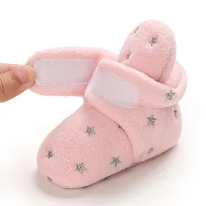 Detail shot of pink fleece baby bootie with velcro strap and star pattern.