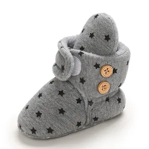 Detalle de bota de bebé gris con patrón de estrellas negras y botones de madera