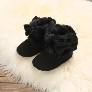 Detalle de botas de invierno negras para bebé con lazo y forro de piel sintética