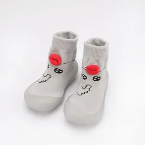 Detail view of grey knitted baby walking shoes with cute cartoon face and red lip design