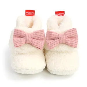 Nahaufnahme von weichen Baby-Winterstiefeln mit rosa gestrickten Schleifen in Cremeweiß