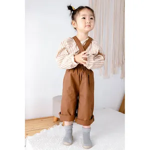 Ein süßes Kleinkind trägt graue, verdickte Baby-Laufsocken-Schuhe in gemütlicher Umgebung