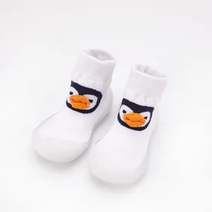 Detail view of white baby knit walker shoes with a cute 3D cartoon penguin face