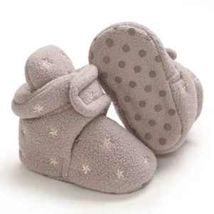 Detail of soft grey fleece baby booties featuring gold star embroidery and non-slip soles