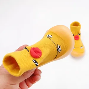 Close-up detail of yellow knit baby walking shoe with cartoon lips and soft rubber sole