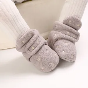 Close-up of warm grey plush baby boots with gold star pattern and velcro straps
