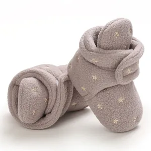 Close-up detail of soft fleece baby booties with embroidered gold stars for winter.