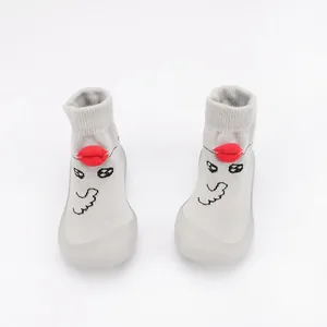 Close-up of grey knitted baby walker shoes with a cute 3D red lip cartoon design