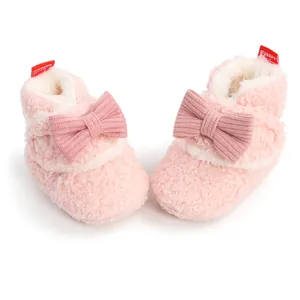 Nahaufnahme von rosa pelzigen Baby-Winterstiefeln mit gestrickter Schleife und Futter