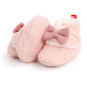 Nahaufnahme der rosa flauschigen Babystiefel mit Schleifendetail für den Winter