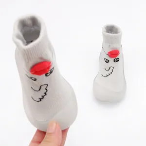 Detail view of grey knit baby walking shoes with cute cartoon face and soft sole.