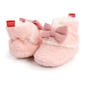 Nahaufnahme von rosa flauschigen Babystiefeln mit großer Strickschleife für den Winterkomfort