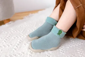 Detail von blaugrünen Baby-Socken-Schuhen mit Dino-Stickerei und dickem Wollfutter