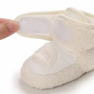 Dettaglio di scarpa bianca per neonati in peluche con chiusura in velcro e fodera morbida