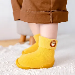 Detailansicht gelber Baby-Socken-Schuhe mit Löwenstickerei und weicher Gummisohle.