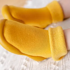 Detailaufnahme von warmen, senfgelben, fleecegefütterten Baby-Laufsocken mit dicker Strickstruktur