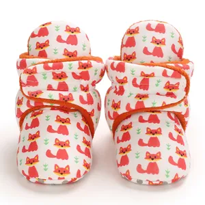 Close-up of cute cartoon fox pattern baby booties with warm orange fleece lining