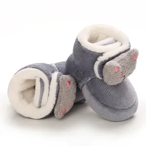 Primer plano de patucos de pana gris para bebé con forro de felpa y gato