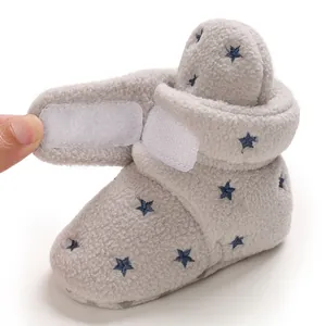 Close-up view of warm grey fleece baby bootie featuring navy star patterns and velcro strap