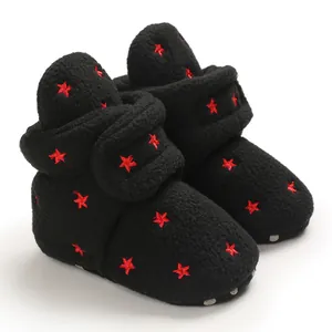 Close-up detail of warm black fleece baby boots with red embroidered stars pattern