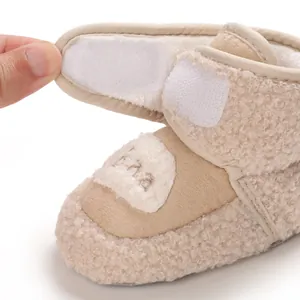 Dettaglio ravvicinato di scarpina in pile beige per neonati con chiusura in velcro regolabile