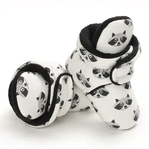 Detailed close-up of soft baby booties with cute raccoon print and black fleece lining