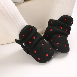 Close-up of black fleece infant snow boots with red star embroidery worn by baby
