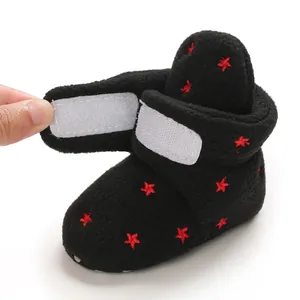 Detailed view of black plush baby bootie with red star embroidery and Velcro closure