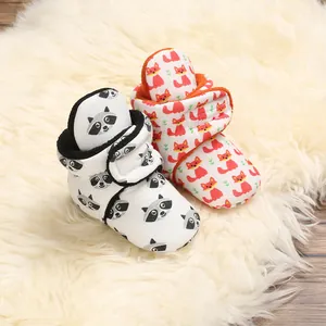 Cute cartoon baby cotton booties with raccoon and fox patterns displayed on a soft plush rug