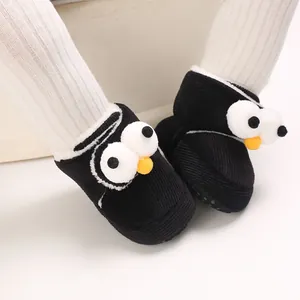 Primer plano de lindos zapatos de bebé de pingüino negro usados por un infante con leggings blancos