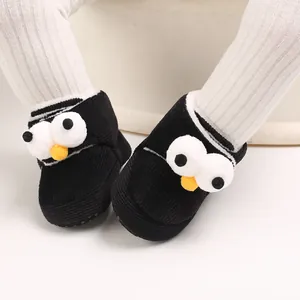Primer plano de lindos zapatos negros de dibujos para bebé con ojos 3D y forro de felpa