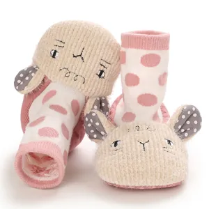 Close-up of pink polka dot baby booties with cute cartoon sheep design